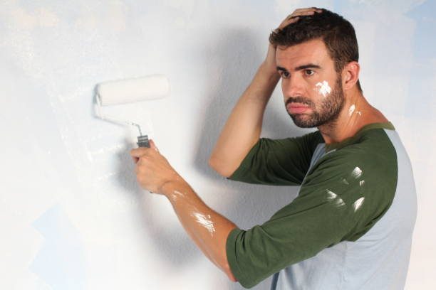 Exhausted man trying to paint a wall.